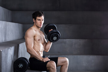 Fototapeta na wymiar Determined attractive young man naked torso exercising with dumbbell.