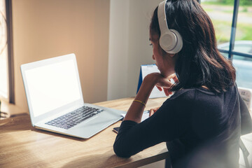 Businesswoman working online at the home office via laptop. Asian young entrepreneurs watching webinars and talking during meeting video conferences calls with team, and using mobile phone.
