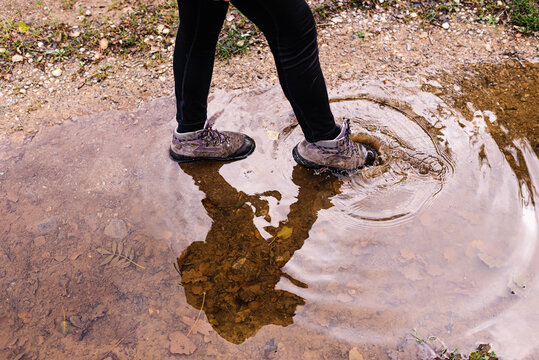 Cropped unrecognizable person playing in mud puddle while making splashes