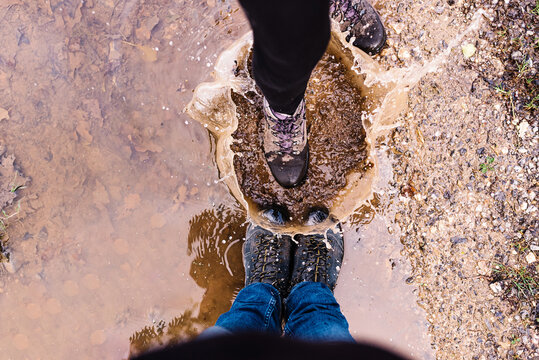 From above of couple of tourists having fun and playing in mud puddle while making splashes