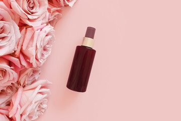 Top view of mockup of unbranded brown plastic spray bottle and pink roses on a pastel pink background. Natural organic spa cosmetics, Body mist. Flower flatlay.