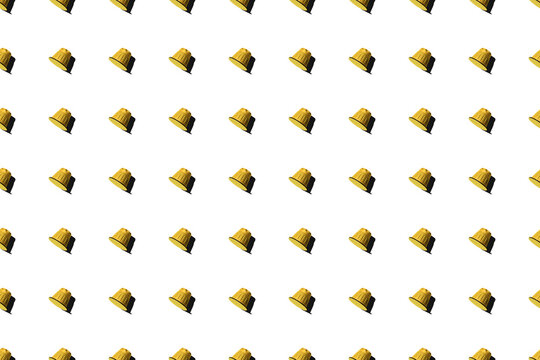 Top view of yellow coffee pods placed in even rows as seamless pattern on white background