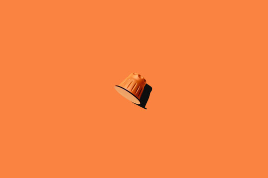 Top view of orange coffee pod placed on orange background