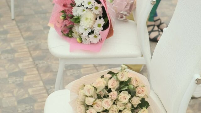 Wedding floral bouquets on white seats zoom in. Outdoors wedding ceremony arrangement