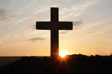 Silhouette of Christian cross outdoors at sunrise. Religion concept