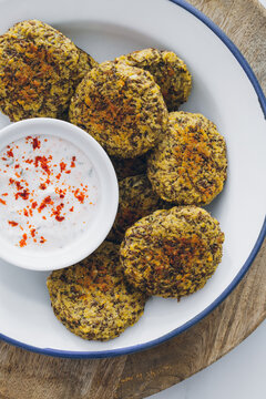 Top view of dish full of lentil falafel served with yogurt sauce on a wooden table