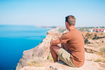 Fototapeta na wymiar Tourist man outdoor on edge of cliff seashore