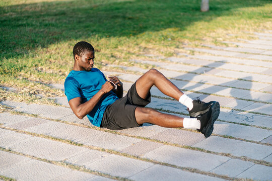 African black man doing abdominal crunch exercises on the floor on a sunny day in the park