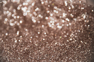 Close up picture of rose gold shade of defocused shimmering glitter fabric. Rose gold color with shiny macro blur effect, as greeting card for holiday. Winter Christmas card with sparkle background.