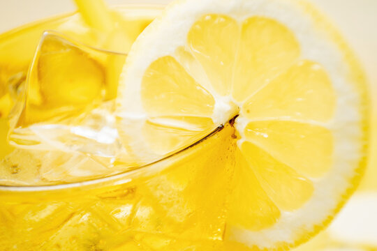From above crop detail of glass of fresh beverage with lemons and kiwi placed in yellow background in studio