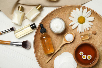 Fototapeta na wymiar Flat lay composition with chamomile and cosmetic products on white wooden table