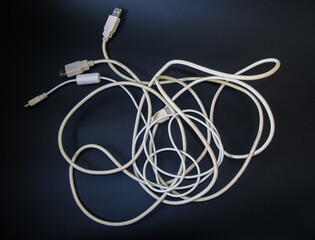 White USB wires for charging your phone and connecting to your computer on a dark background.
