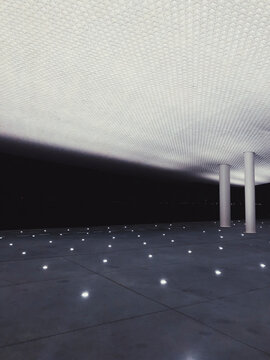 Contemporary facade of building and stone ground with glowing lamps constructed in futuristic style in evening