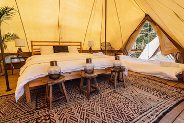 Luxurious interior of spacious camping tent with cozy beds near carpet and potted plants in tropical country