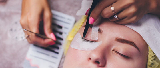 Bunch of artificial eyelashes in tweezers. Extensions of artificial eyelash, process close up....