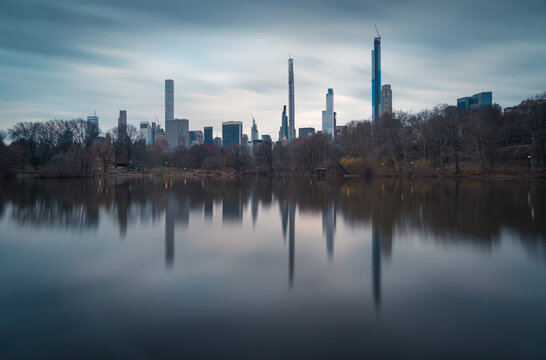 Magnificent view of contemporary skyscrapers of New York City reflected in calm river water in cloudy evening