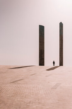 Unrecognizable person standing between stone columns on spacious square near contemporary building of Champalimaud Foundation in Lisbon