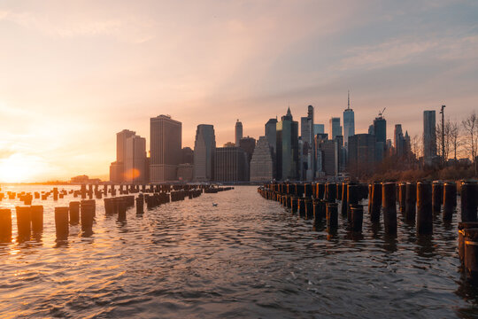 Manhattan skyline and poles of famous Brooklyn Bridge Park at sunset time