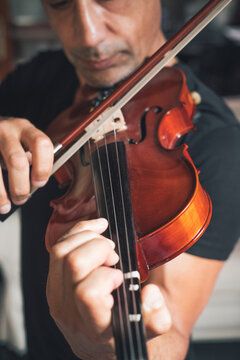 Cropped unrecognizable talented focused Hispanic male violinist playing violin during rehearsal