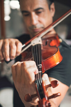 Talented focused Hispanic male violinist playing violin during rehearsal