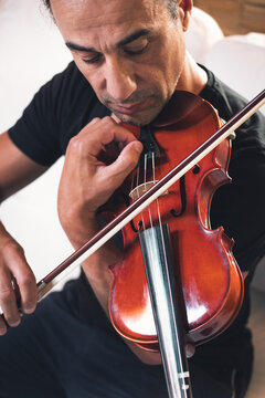 From above talented focused Hispanic male violinist playing violin during rehearsal