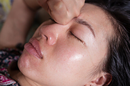 Sick ethnic female lying on bed and crying while having flu and headache