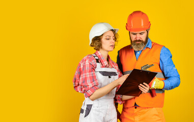 Family counting finances for renovation. Woman and man wear safety hard hat. Redevelopment of home. Renovation concept. Couple planning changes renovation apartment. Couple looking at documents