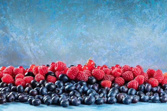 Fresh blueberries, redcurrants and raspberries texture, side view with a place for text