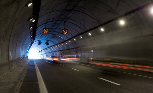 Fototapeta Modern road tunnel with artificial lightning and traffic light trails in long exposure