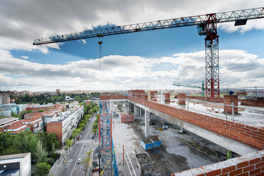 Majestic view of spacious construction site with tall crane surrounded by brick buildings