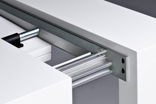 From above of open apparatus in form of drawer with white smooth surface and stainless steel parts inside with solid structure fixed with bolts