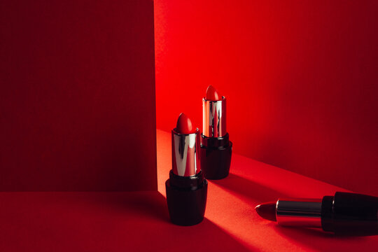 Set of bright red lipsticks in elegant shiny tubes placed on red background