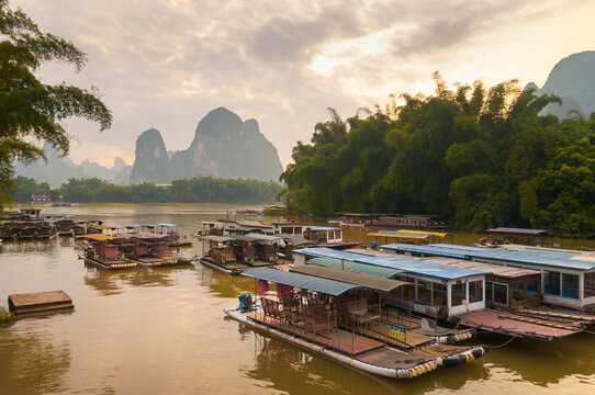 Majestic landscape of bay with shabby traditional vessels on background of rocky mountains and amazing sundown in Yangshuo County in China