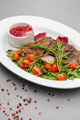 Grilled maso with vegetables and rosemary on a white plate.