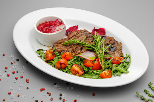 Grilled maso with vegetables and rosemary on a white plate.