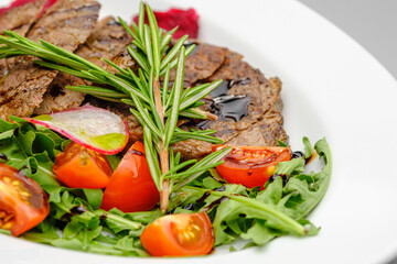 Grilled maso with vegetables and rosemary on a white plate.