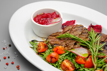 Grilled maso with vegetables and rosemary on a white plate.