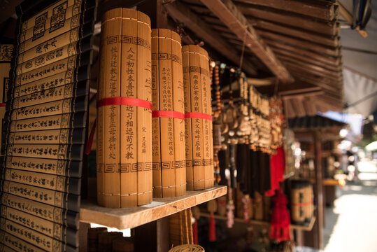Handmade bamboo slips with inscriptions placed on wooden shelf on local market with traditional souvenirs