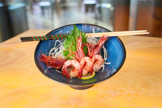 Traditional Sashimi with prawns served with daikon and slice of fresh lime and placed on table