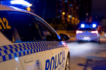 Contemporary police vehicle with siren light on the road on background of amazing night cityscape
