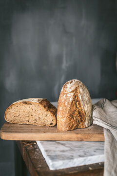 From above cut in half loaf of delicious homemade bread placed on piece of cloth on table in kitchen
