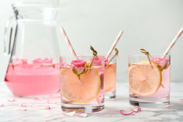 Refreshing drink with lemon and rose on white marble table