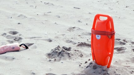 Lifeguard board stuck in the sand on the beach, ready for rescue.