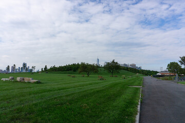 Lawn with trees, benches and view of Manhattan in the background. Park in the Governors Island