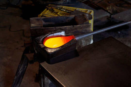From above of burning hot liquid glass mass on blowpipe in process of producing shisha glass base