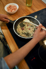 Close up of man cooking sauteed onion and garlic in the frying pan. Man preparing dinner. Cooking at home concept