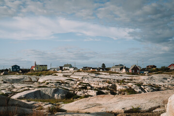 Lovely cottages located in stony terrain against cloudy sky on dull day in Peggys Cove, Canada