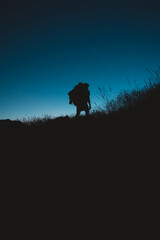 Silhouette of backpacker hiking under the moonlight