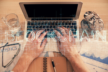 Double exposure of man's hands typing over computer keyboard and crypto currency theme hologram drawing. Top view. Blockchain concept.