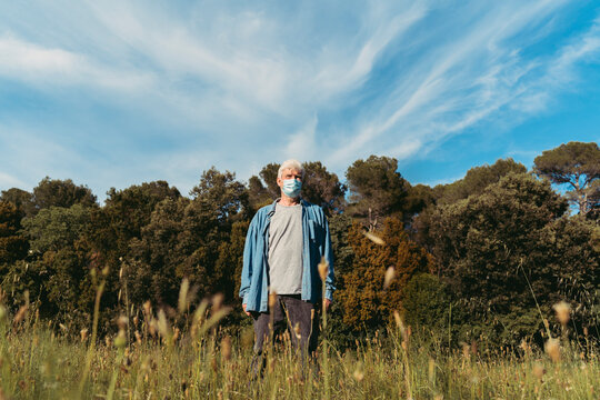 Senior man with protective mask standing on meadow